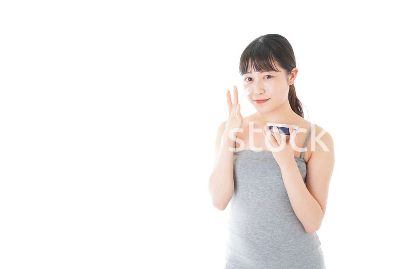 顔にクリームを塗る若い女性