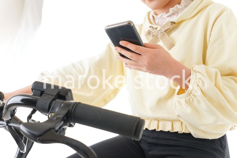自転車でスマホを使う若い女性
