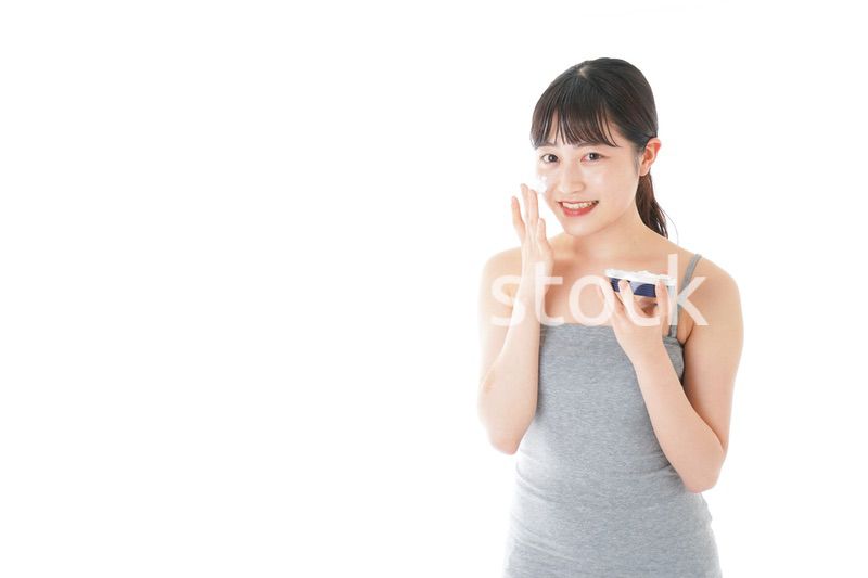 顔にクリームを塗る若い女性