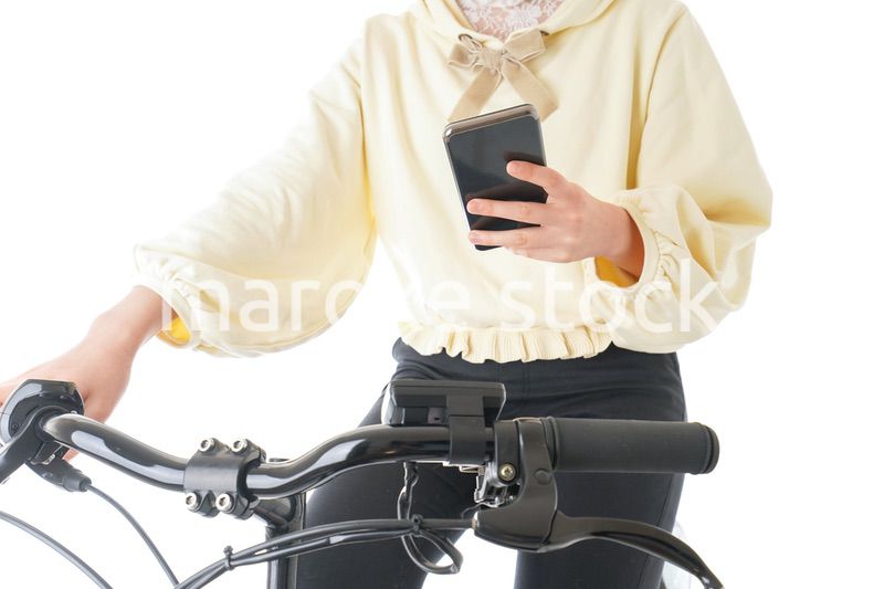 自転車でスマホを使う若い女性