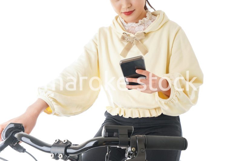 自転車でスマホを使う若い女性