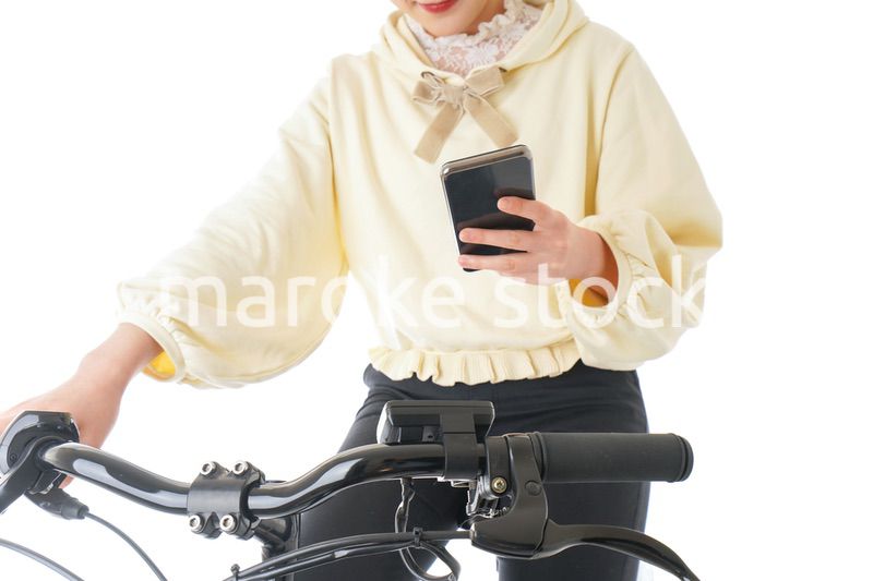 自転車でスマホを使う若い女性