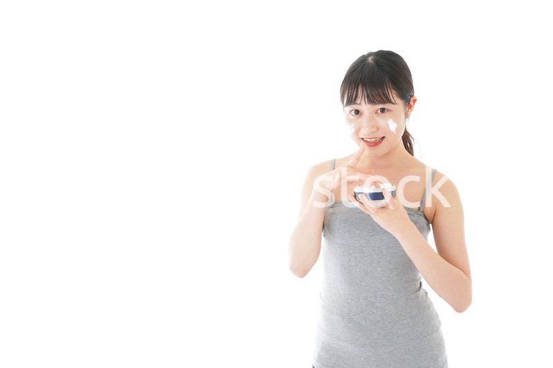 顔にクリームを塗る若い女性