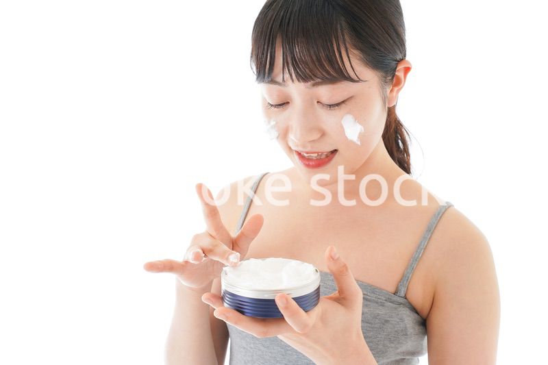 顔にクリームを塗る若い女性