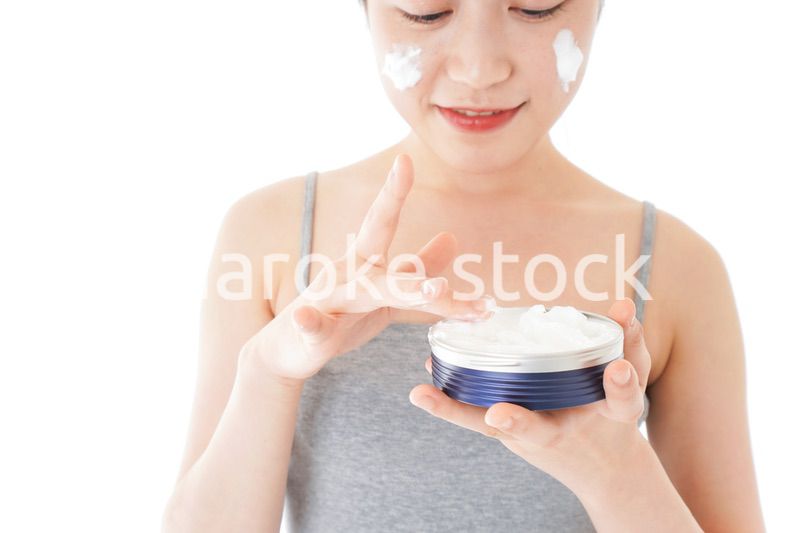 顔にクリームを塗る若い女性