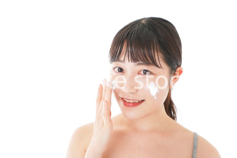 顔にクリームを塗る若い女性