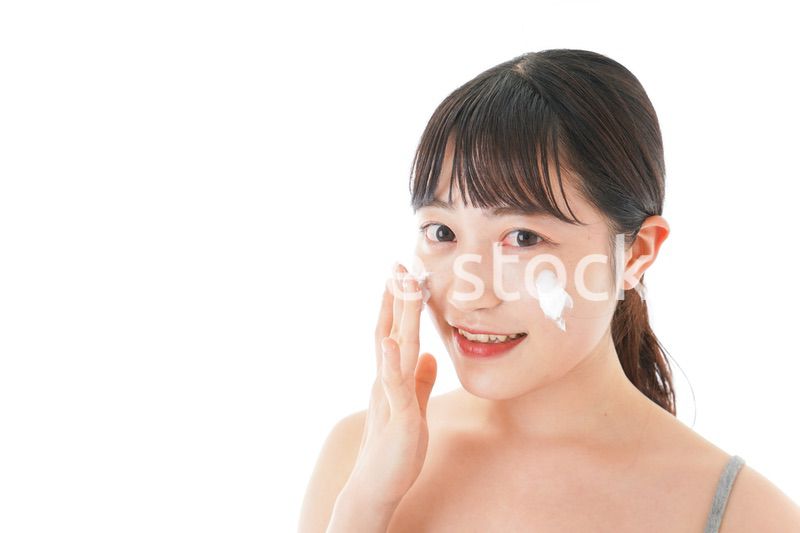 顔にクリームを塗る若い女性