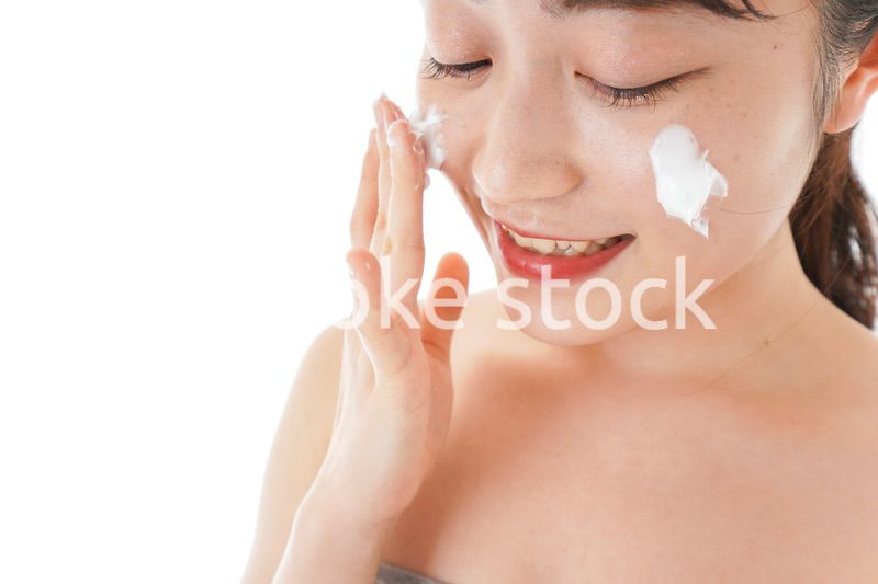 顔にクリームを塗る若い女性