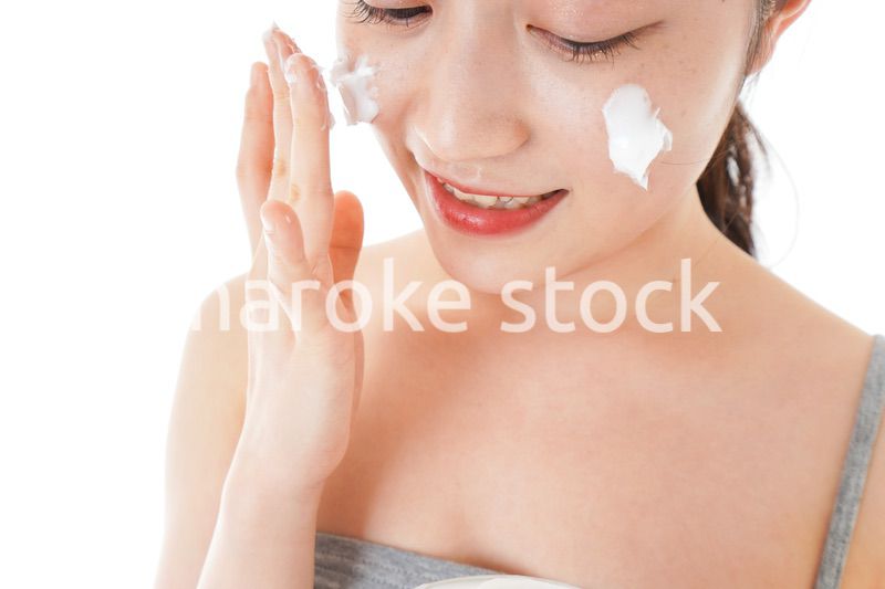 顔にクリームを塗る若い女性