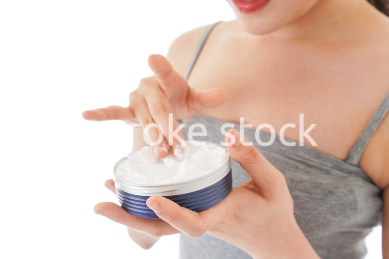 顔にクリームを塗る若い女性