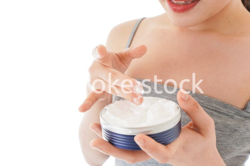 顔にクリームを塗る若い女性