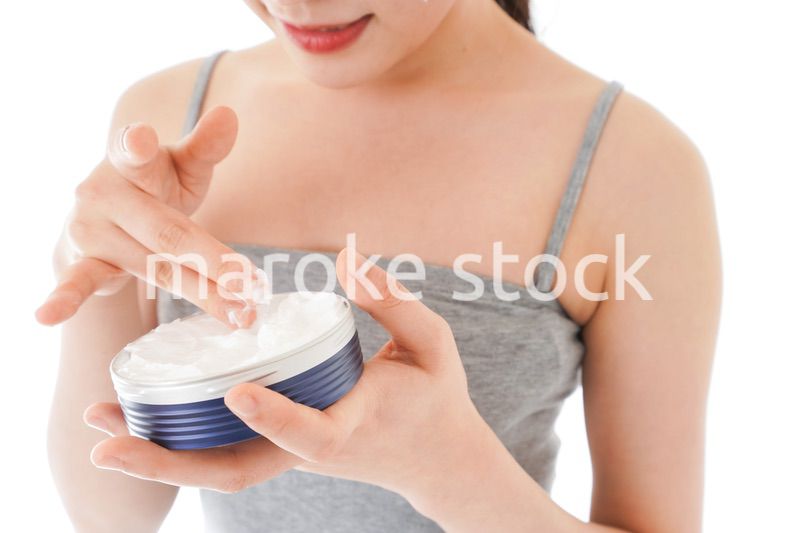 顔にクリームを塗る若い女性