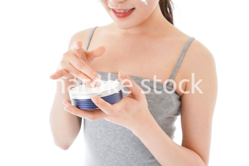 顔にクリームを塗る若い女性