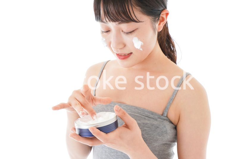 顔にクリームを塗る若い女性