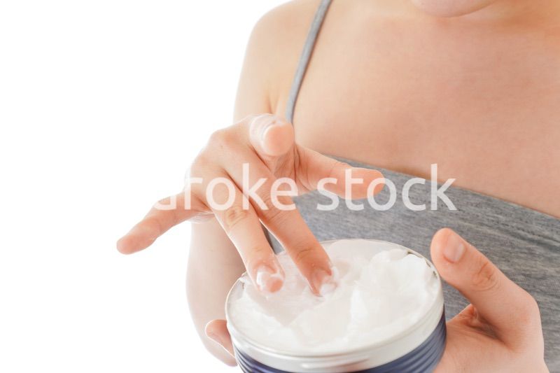 顔にクリームを塗る若い女性