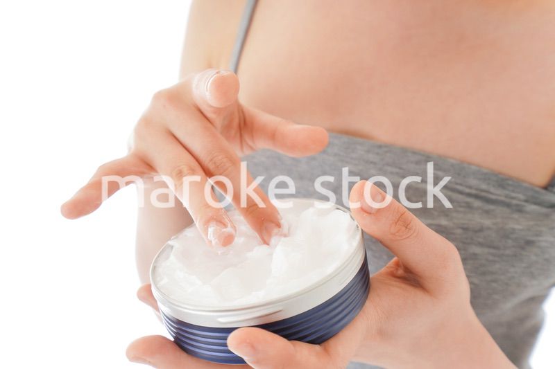 顔にクリームを塗る若い女性