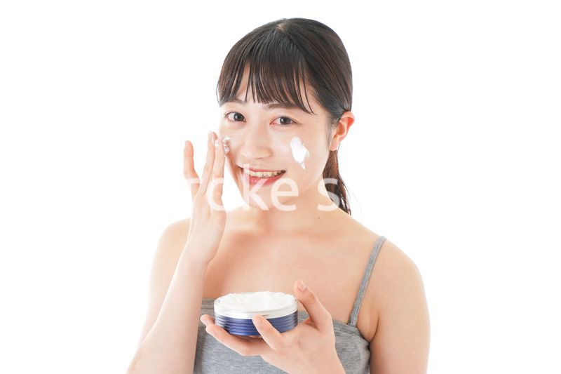顔にクリームを塗る若い女性