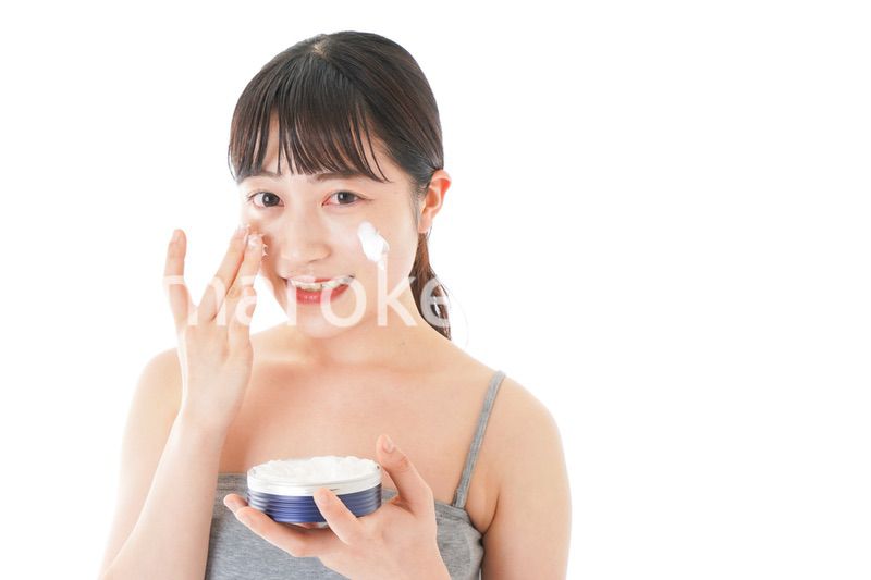 顔にクリームを塗る若い女性
