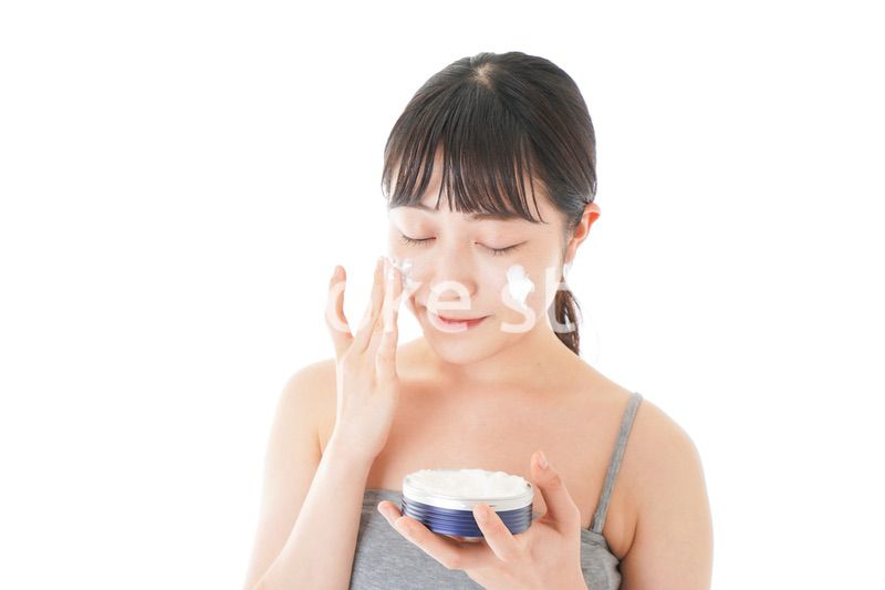 顔にクリームを塗る若い女性