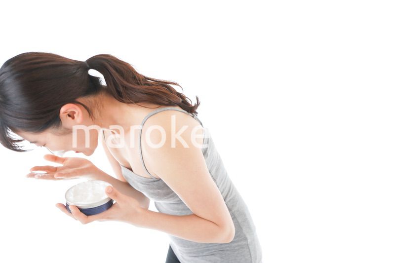顔にクリームを塗る若い女性