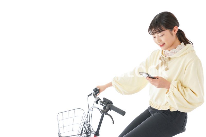 自転車でスマホを使う若い女性