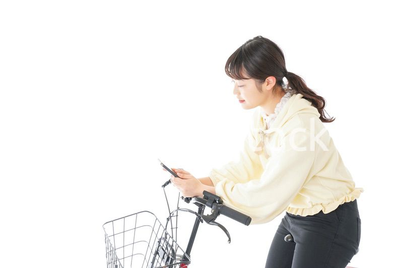 自転車でスマホを使う若い女性