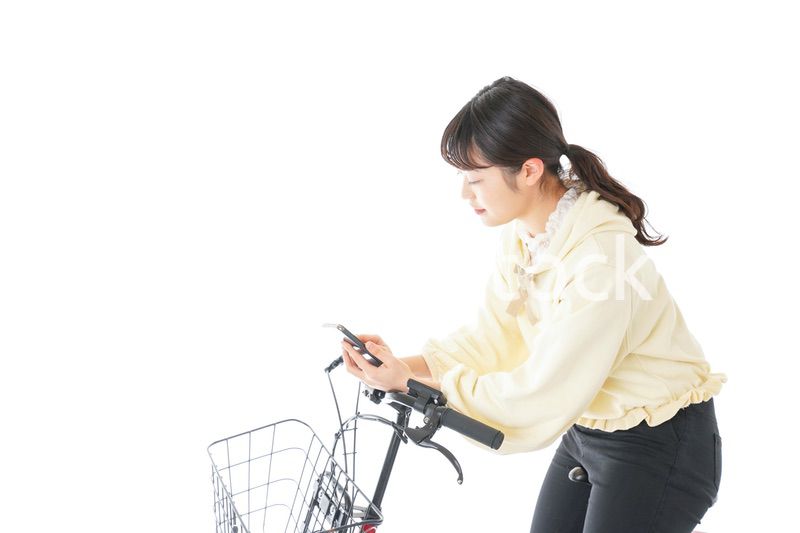 自転車でスマホを使う若い女性