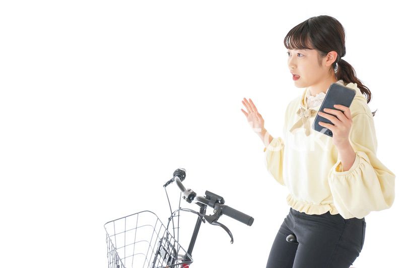 自転車でスマホを使う若い女性