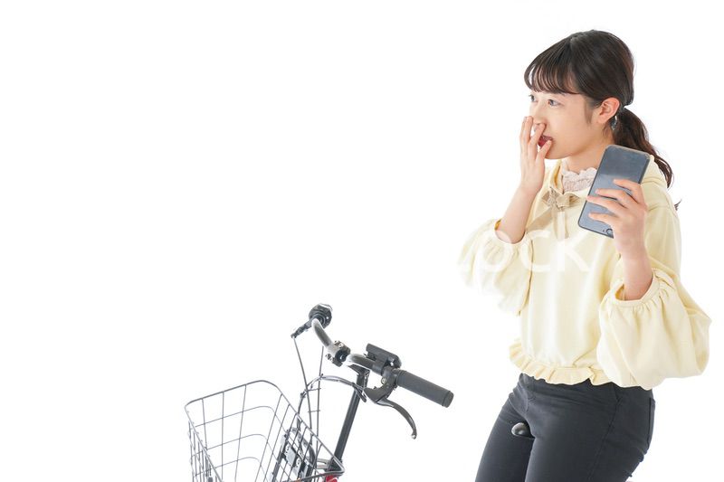 自転車でスマホを使う若い女性