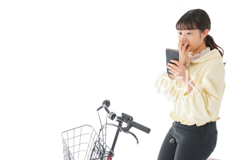 自転車でスマホを使う若い女性