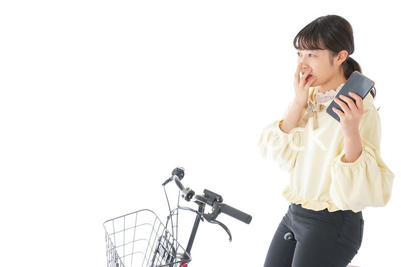 自転車でスマホを使う若い女性