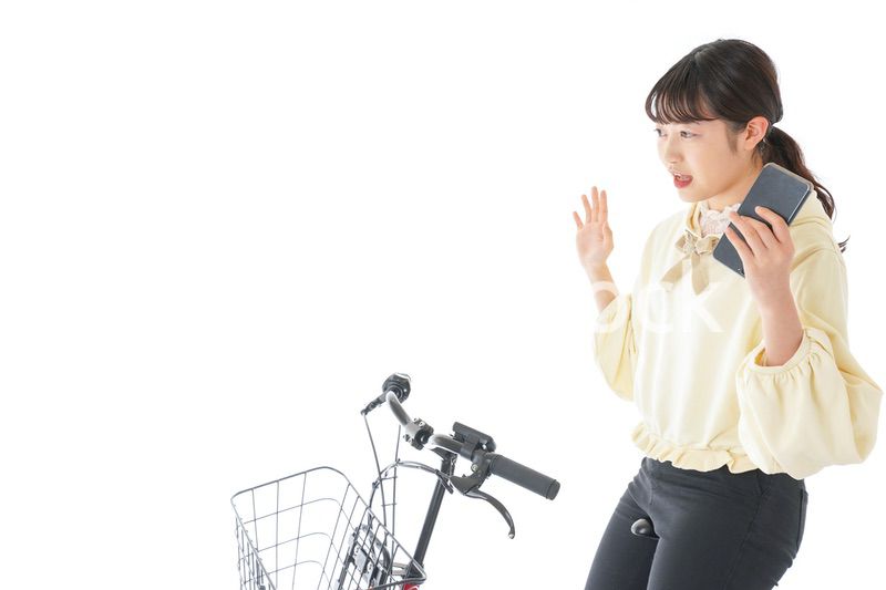 自転車でスマホを使う若い女性