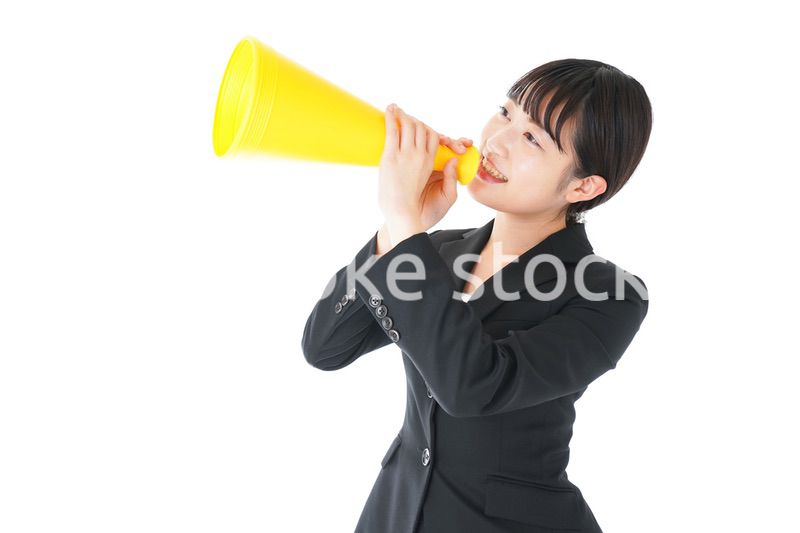 メガフォンで応援をするスーツを着たビジネスウーマン