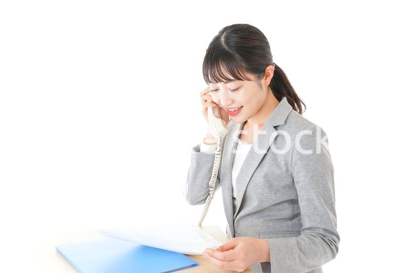 オフィスで固定電話を使う若いビジネスウーマン