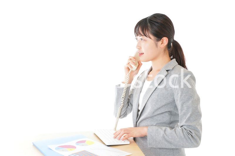 オフィスで固定電話を使う若いビジネスウーマン