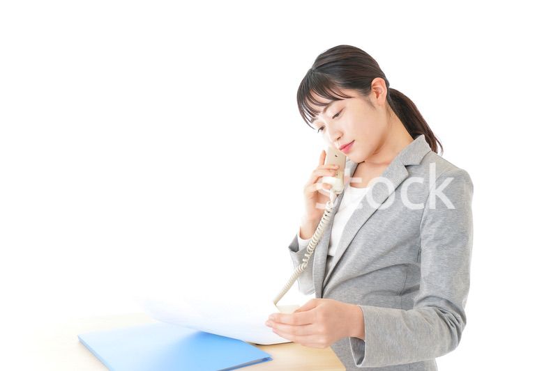 オフィスで固定電話を使う若いビジネスウーマン