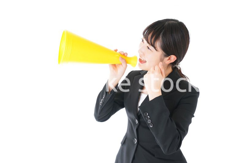 メガフォンで応援をするスーツを着たビジネスウーマン