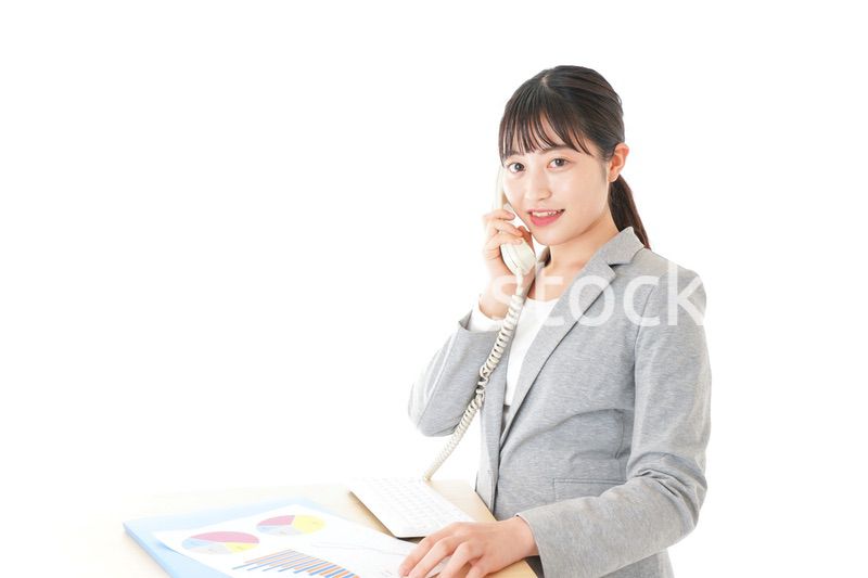 オフィスで固定電話を使う若いビジネスウーマン