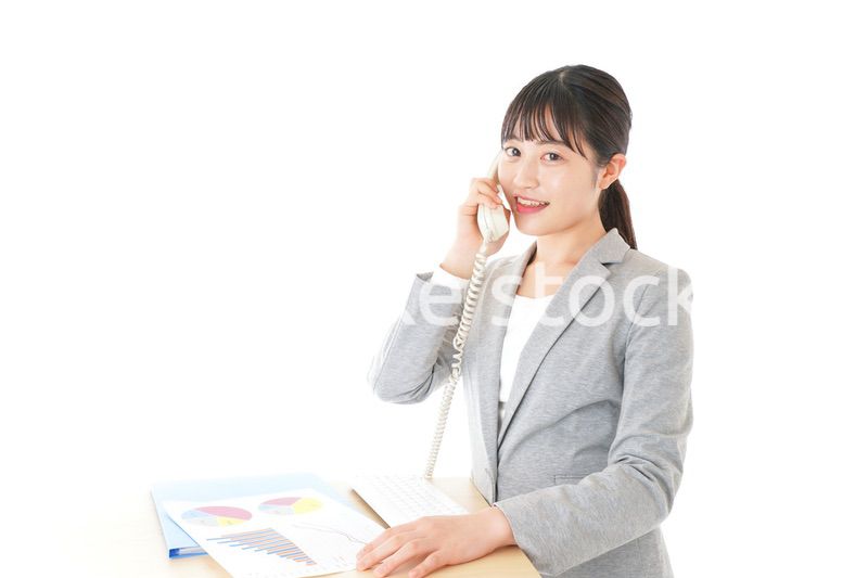 オフィスで固定電話を使う若いビジネスウーマン