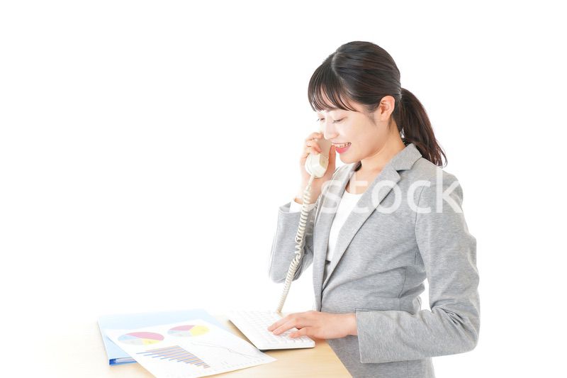 オフィスで固定電話を使う若いビジネスウーマン