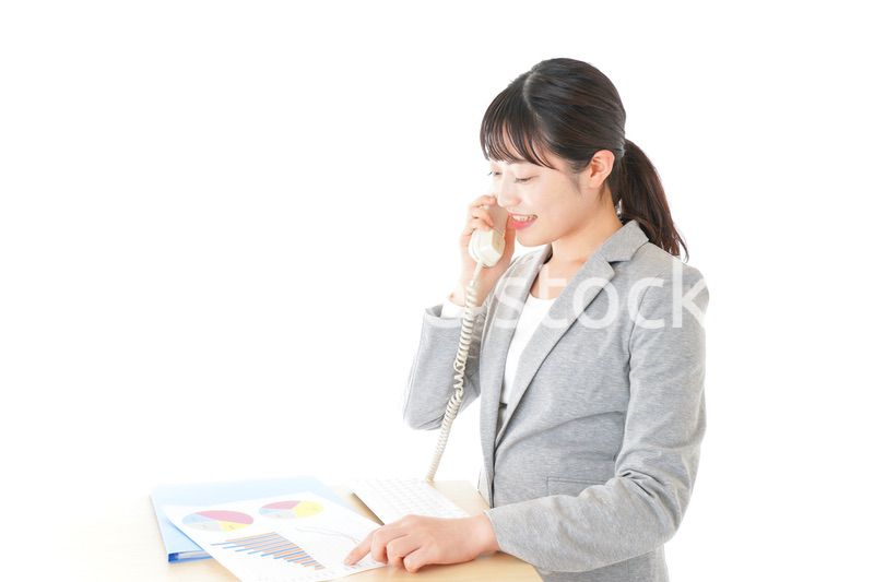 オフィスで固定電話を使う若いビジネスウーマン