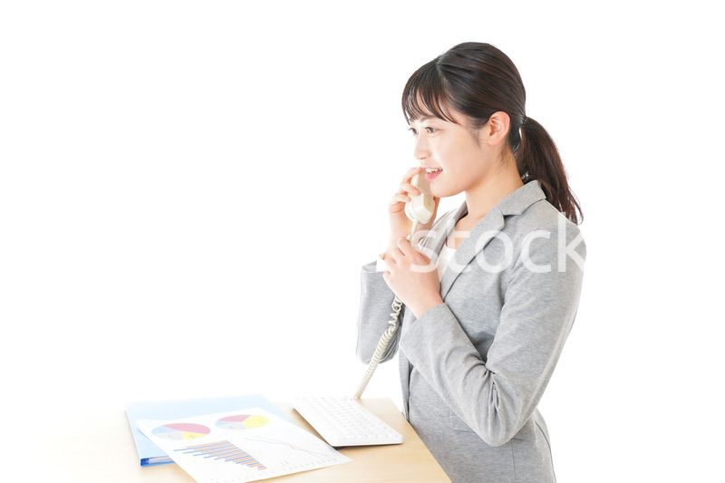 オフィスで固定電話を使う若いビジネスウーマン