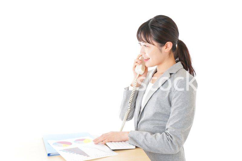 オフィスで固定電話を使う若いビジネスウーマン