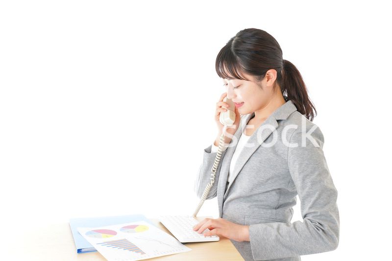 オフィスで固定電話を使う若いビジネスウーマン