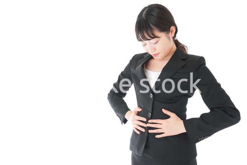 腹痛に苦しむ若いビジネスウーマン