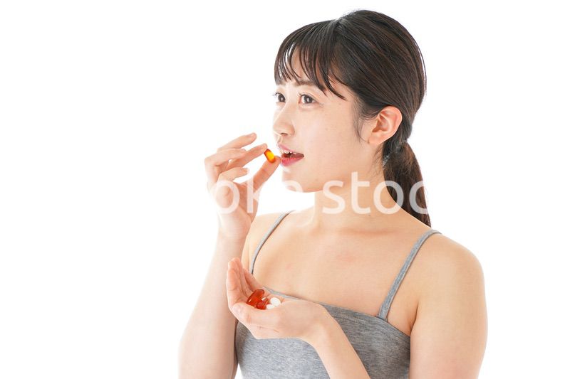 薬・サプリメントを服用する若い女性