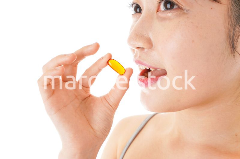薬・サプリメントを服用する若い女性