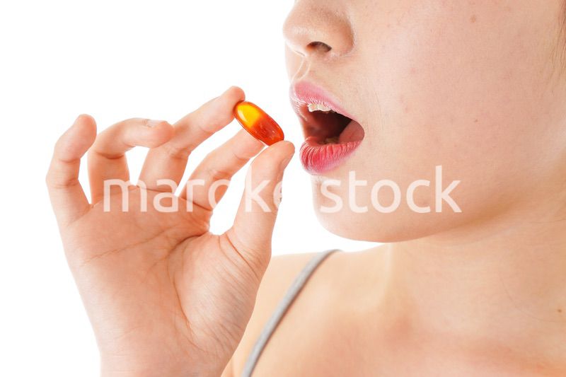 薬・サプリメントを服用する若い女性