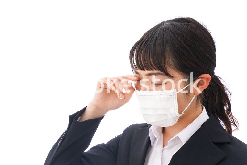 花粉症・風邪・インフルエンザに苦しみマスクをする若い女性