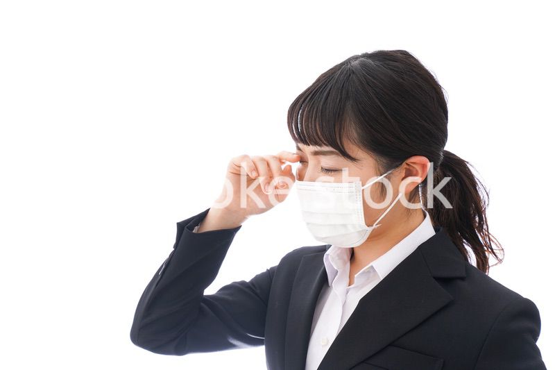 花粉症・風邪・インフルエンザに苦しみマスクをする若い女性
